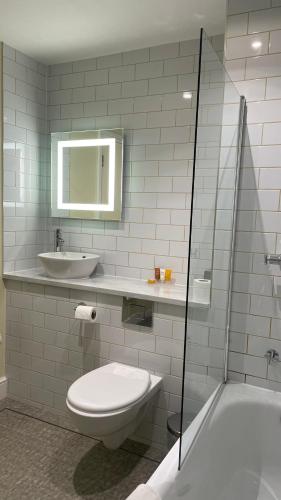 a bathroom with a toilet and a sink and a tub at Hellidon Lakes Hotel in Daventry