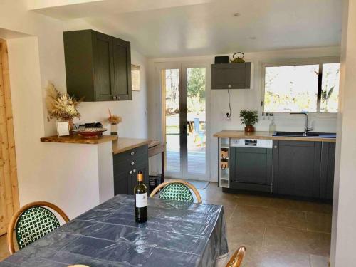- une cuisine avec une table et une bouteille de vin dans l'établissement Maison bois tout confort proche du lac et de l'océan, à Hourtin