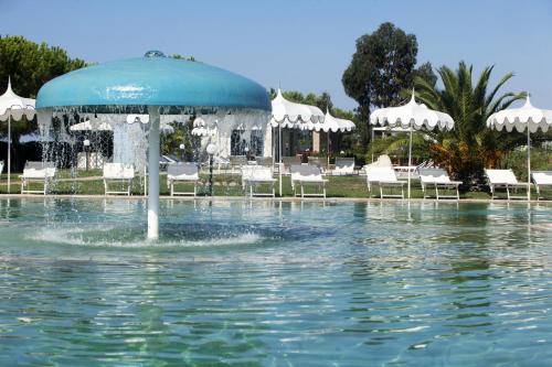a swimming pool with an umbrella in the water at Fattoria Maremmana in Marina di Grosseto
