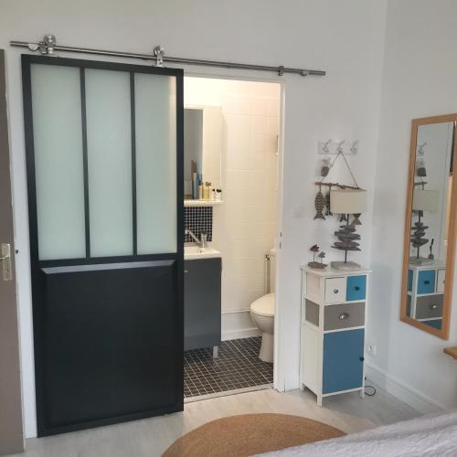 La salle de bains est pourvue d'une porte noire et de toilettes. dans l'établissement Joli appt cocooning au pied des dunes, à Berck-sur-Mer