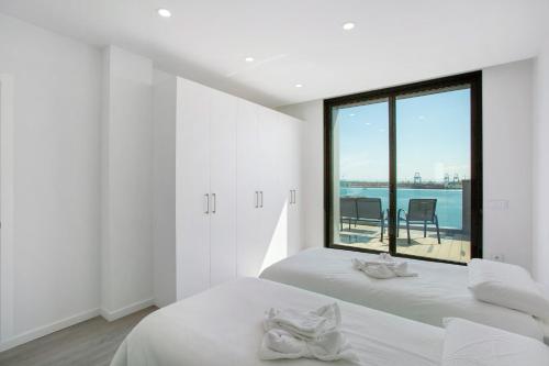 een witte kamer met 2 bedden en een groot raam bij Wonderful penthouse city and beach in Las Palmas de Gran Canaria