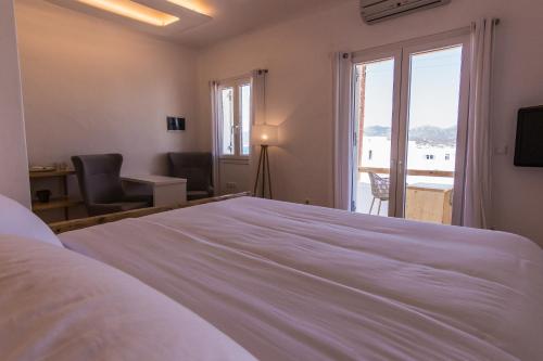 ein Schlafzimmer mit einem großen weißen Bett und einem Fenster in der Unterkunft SALT SUITES MILOS in Pollonia