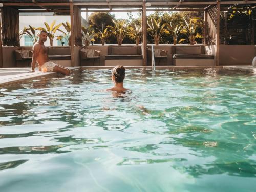 un hombre y una mujer sentados en una piscina en Barefoot Hotel Mallorca en Portocolom