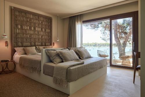 a bedroom with a large bed and a large window at Barefoot Hotel Mallorca in Portocolom