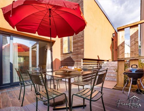 een tafel en stoelen met een rode parasol op een patio bij Marvel House - Disneyland 5min, Private Parking, Terrace in Magny-le-Hongre