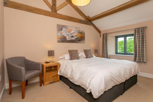a bedroom with a bed and a chair and a window at Brockram & Keld Barns in Kirkby Stephen