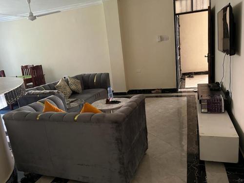 een woonkamer met een bank en een televisie bij Lizzy B Classic Apartments Mtwapa in Mombasa