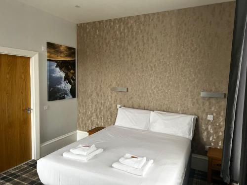 a bedroom with a white bed with two towels on it at Crown Hotel & Bar in Inverness