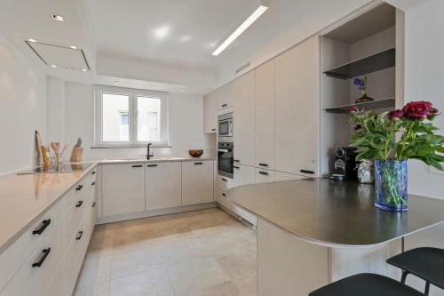 een witte keuken met een vaas met bloemen op een aanrecht bij Huswell - Panoramic seaview apartment in 't Zoute in Knokke-Heist