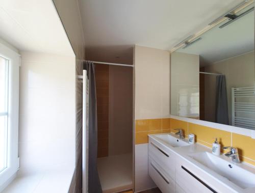 een badkamer met 2 wastafels en een spiegel bij le Moulin de la Raterie in Charensat