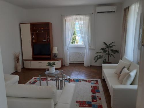 a living room with white furniture and a television at APARTMENT VOLOSKO - 50m to the sea in Opatija