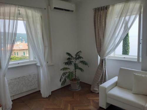 una sala de estar con cortinas blancas, una silla y una planta en APARTMENT VOLOSKO - 50m to the sea en Opatija