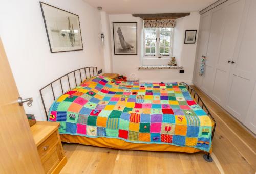 uma cama com uma colcha colorida num quarto em Moose Cottage em Newton Ferrers