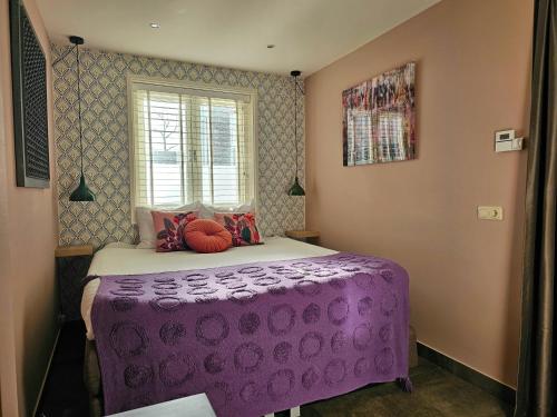 fioletowe łóżko w pokoju z oknem w obiekcie Zandvoort at Home I Free parking & Airco w Zandvoort