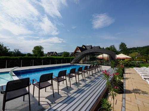 a row of chairs sitting next to a swimming pool at Hotel Liptakówka in Białka Tatrzanska