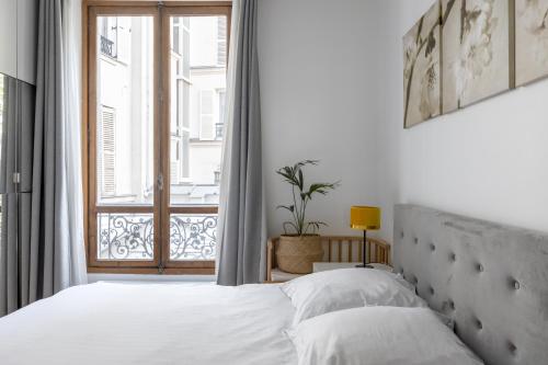 une chambre avec un lit et une grande fenêtre dans l'établissement Veeve - Porcelain Pelouse, à Paris