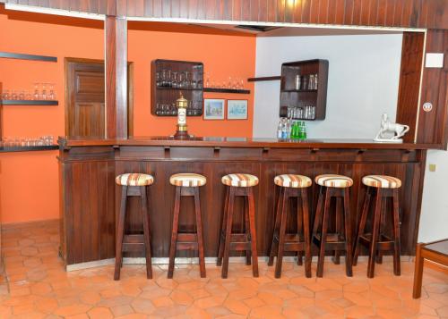 a bar with orange walls and brown stools at LagosMar Story Hotel in Lagos