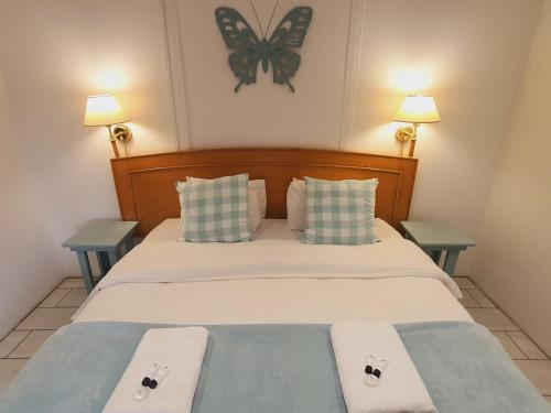 a bedroom with a bed with two tables and a butterfly on the wall at Rhino Manor in Vanderkloof
