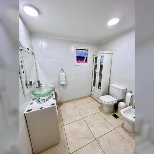 a white bathroom with a sink and a toilet at Corinto Tempo in Esquel