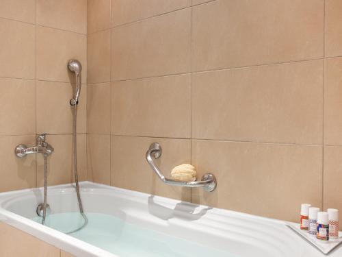 uma banheira na casa de banho com um chuveiro em Grecotel Filoxenia Hotel em Kalamata