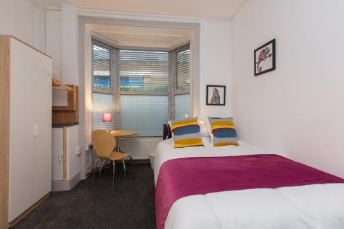 a bedroom with a bed and a table and a window at 8 Samuel Street in Crewe