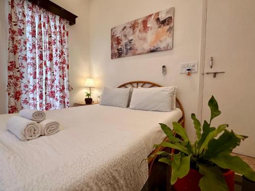 a bedroom with a bed with white sheets and a plant at Leisure By The Beach Goa in Benaulim