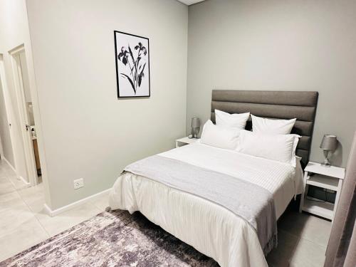 a white bedroom with a large bed and a rug at Shamah in Pretoria