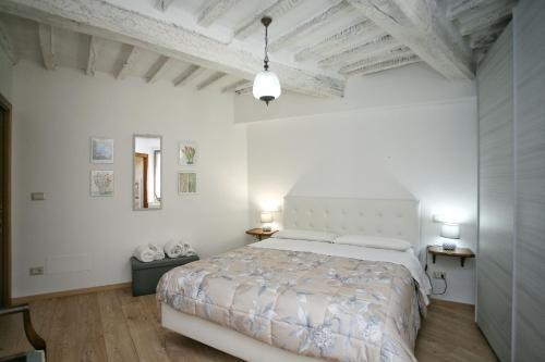 a white bedroom with a bed and two lamps at Appartamento il Girasole in Cetona