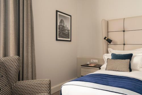 a bedroom with a bed and a chair at Cerretani Hotel Firenze - MGallery Collection in Florence