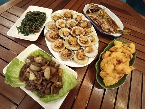 a wooden table with plates of food on it at Larapan Water Village 仙本那乐乐棒水屋 in Semporna