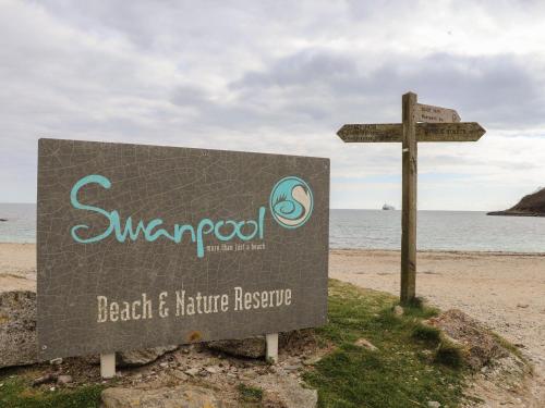 a sign on the beach next to the ocean at Swans Nest in Falmouth