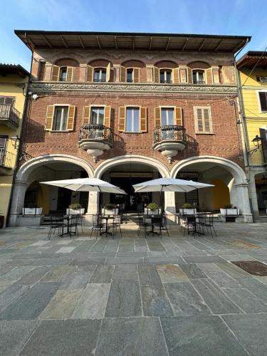 a building with tables and umbrellas in front of it at Giuditta B&B stanza in Ciriè