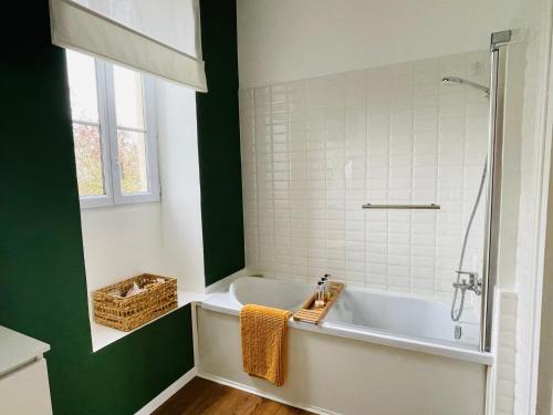 a bathroom with a white tub and a green wall at Le Manoir des Doyens in Bayeux