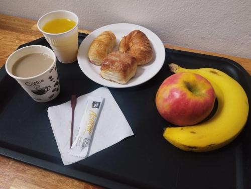 una bandeja con una manzana, un plátano y un plato de comida en Hotel Romi, en Colonia del Sacramento