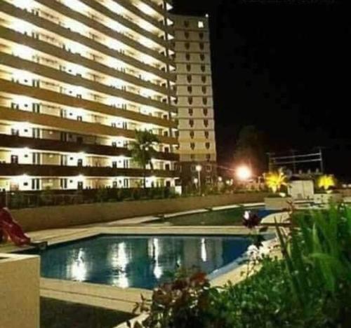 a swimming pool in front of a tall building at night at Saekyung Village One-Phase 2 in Lapu Lapu City