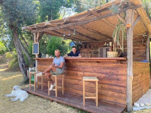 two men sitting at a bar with a dog at Habitat Eco Farm in Sorrento