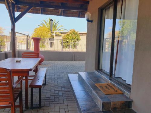 a patio with a table and chairs and a window at Rhino Manor in Vanderkloof