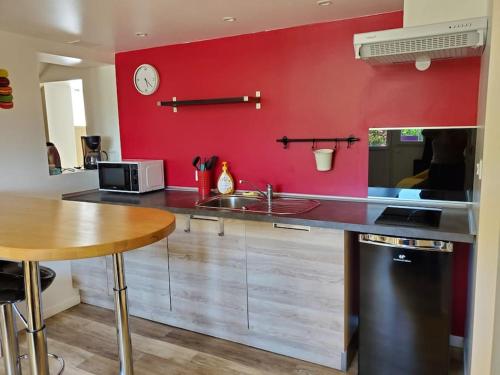 eine Küche mit einer Theke und einer roten Wand in der Unterkunft La bastille 4 in Saintes