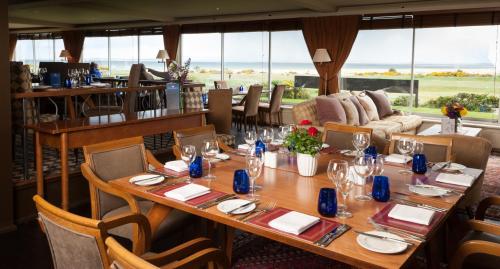 a dining room with a table and chairs and windows at Royal Golf Hotel in Dornoch
