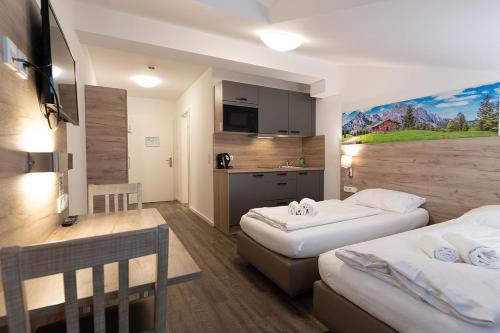 a hotel room with two beds and a kitchen at Aparthotel Oberfeld West München in Straßlach-Dingharting