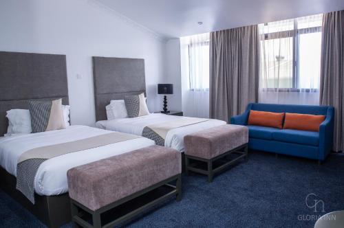 a hotel room with two beds and a blue couch at Gloria Inn Hotel - Ndola in Ndola