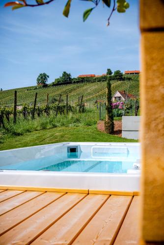 a jacuzzi tub on a deck with a vineyard at Klöchberg Relaxing & Living in Klöch