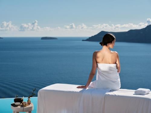 a bride sitting on a table overlooking the water at Olvos Luxury Suites in Oia