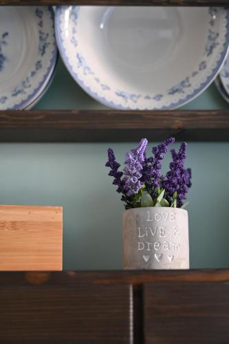 a vase with purple flowers on a shelf with plates at Koskinou Traditional Houses in Koskinou