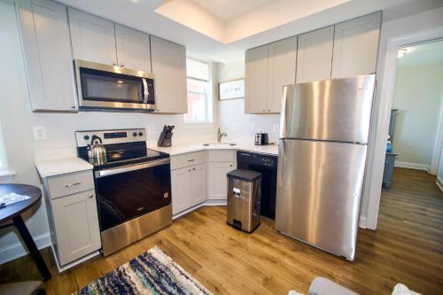 a kitchen with white cabinets and a stainless steel refrigerator at The Vianny:Petite Modern Lodge in Washington, D.C.