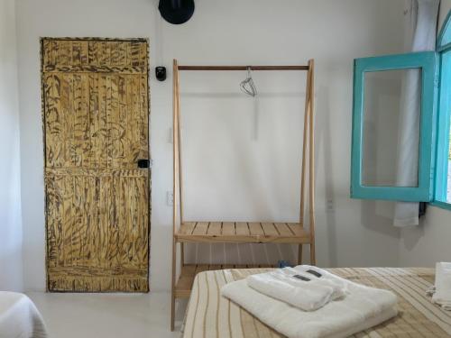 a room with a wooden door with towels on a bed at Vila Rita Hostel Arraial d'Ajuda in Arraial d'Ajuda