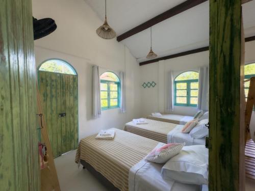 a bedroom with three beds and two windows at Vila Rita Hostel Arraial d'Ajuda in Arraial d'Ajuda