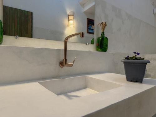 a kitchen sink with a faucet and a vase with flowers at Vila Rita Hostel Arraial d'Ajuda in Arraial d'Ajuda
