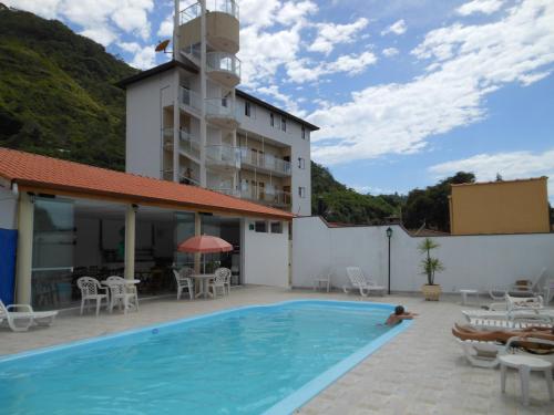 a person swimming in a swimming pool next to a building at Pousada Pescador in Ubatuba