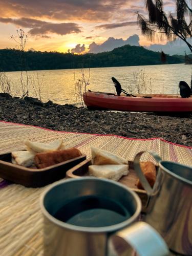 a table with food and a boat on the water at Treehouse Chalets - Luxury getaway within a short distance of Ella in Belihul Oya